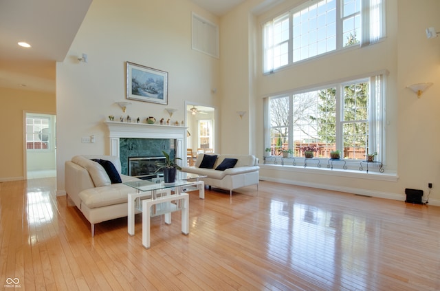 living room with light hardwood / wood-style floors, a high ceiling, and plenty of natural light