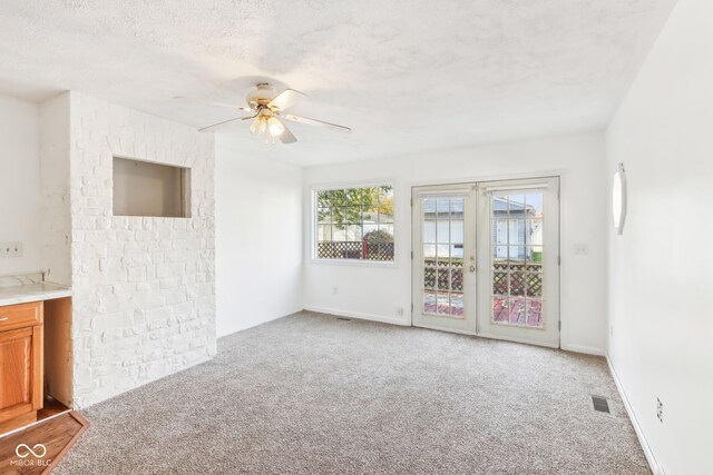 unfurnished living room featuring french doors, light carpet, a textured ceiling, and ceiling fan