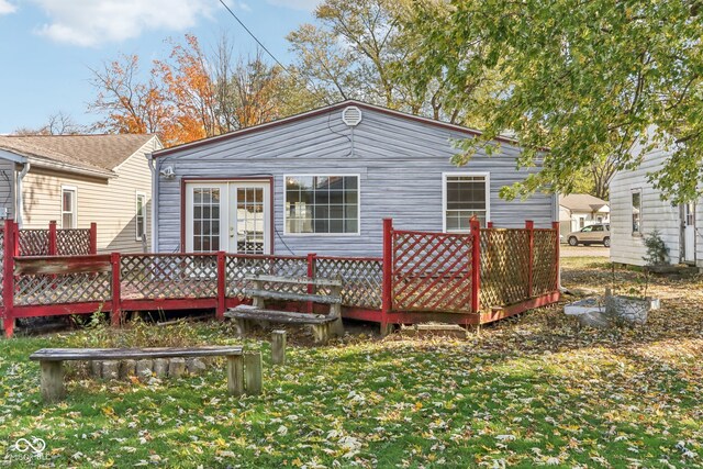 back of house with a deck and a lawn