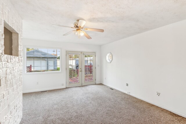 empty room featuring french doors, carpet, and a textured ceiling