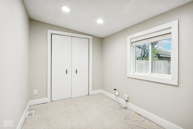 unfurnished bedroom with a closet and light colored carpet