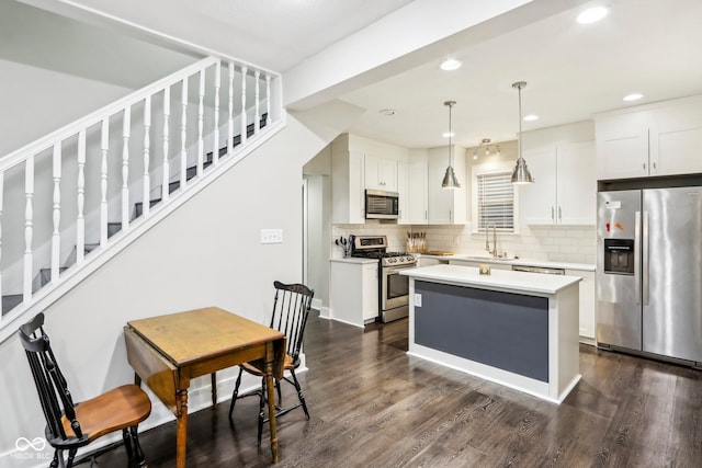 kitchen with white cabinets, stainless steel appliances, decorative light fixtures, and a center island