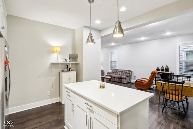 kitchen with dark hardwood / wood-style flooring, a center island, hanging light fixtures, and white cabinets