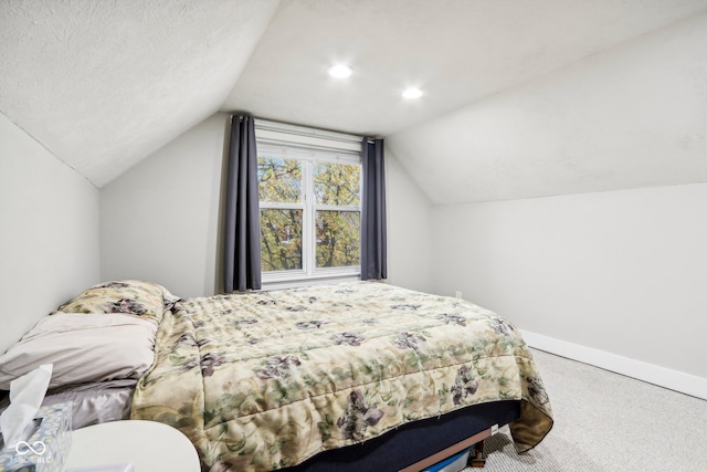 bedroom featuring carpet, lofted ceiling, and a textured ceiling