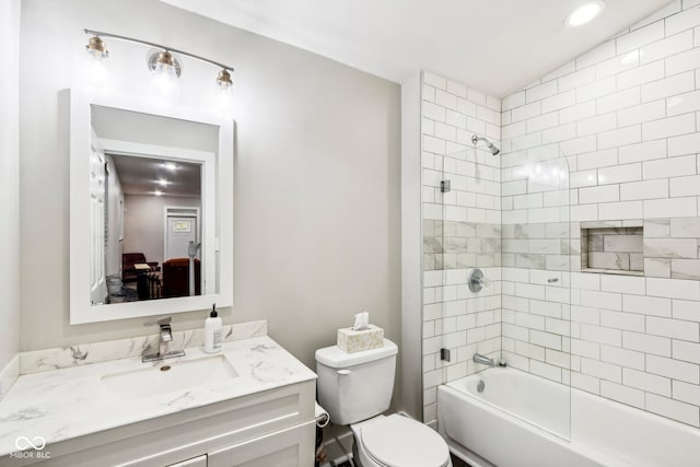 full bathroom featuring vanity, tiled shower / bath, and toilet