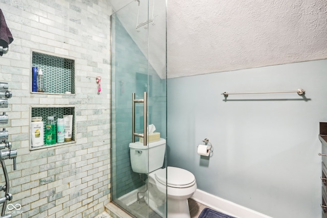 bathroom featuring a textured ceiling, vanity, tiled shower, toilet, and vaulted ceiling