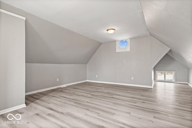 additional living space with light hardwood / wood-style floors and vaulted ceiling