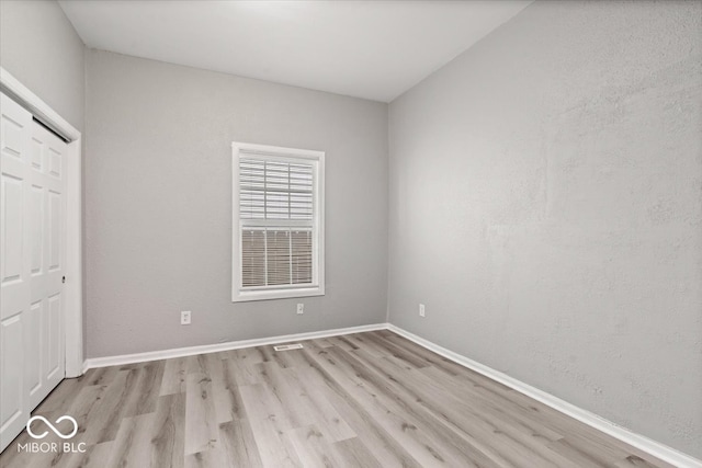 unfurnished bedroom featuring light hardwood / wood-style flooring and a closet