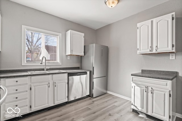 kitchen featuring appliances with stainless steel finishes, white cabinetry, sink, and light wood-type flooring