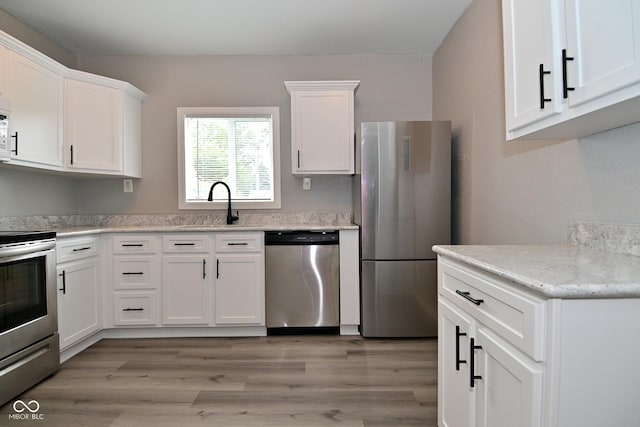 1709 Hoyt Ave, Indianapolis, IN 46203 - kitchen featuring stainless steel appliances, white cabinets, light wood finished floors, and light stone countertops