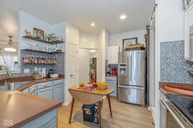 kitchen featuring sink, light wood-type flooring, hanging light fixtures, white cabinetry, and stainless steel refrigerator with ice dispenser