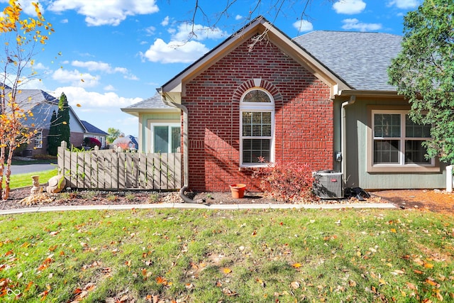 view of front of home with cooling unit and a front lawn