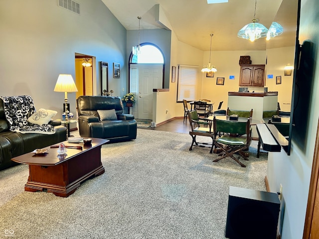 carpeted living room featuring high vaulted ceiling and a chandelier