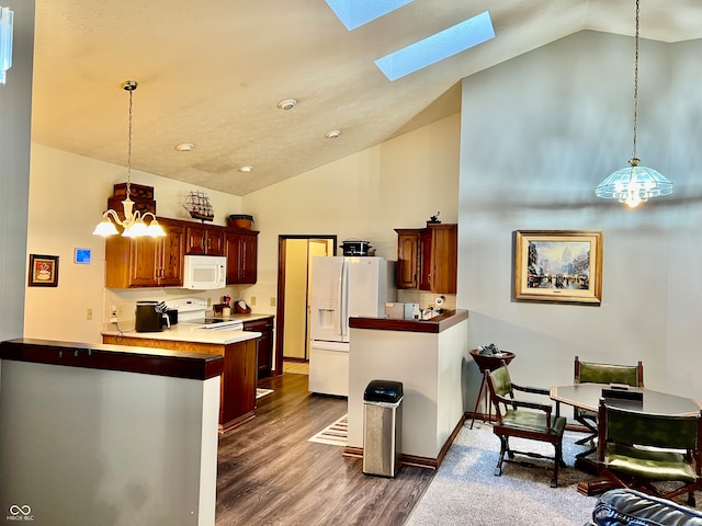 kitchen featuring kitchen peninsula, hanging light fixtures, a notable chandelier, white appliances, and dark hardwood / wood-style flooring