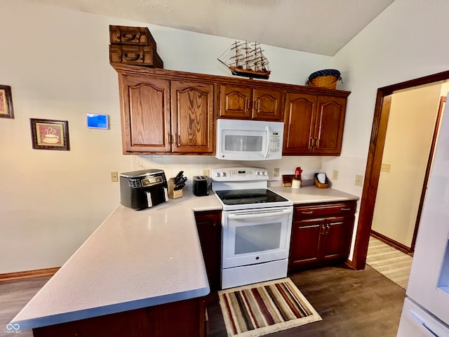 kitchen featuring white appliances, dark wood-type flooring, and vaulted ceiling