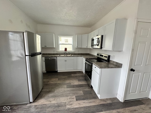 kitchen featuring white cabinetry, stainless steel appliances, dark wood-type flooring, and a textured ceiling