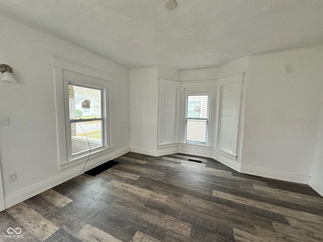 empty room featuring a textured ceiling and dark hardwood / wood-style flooring