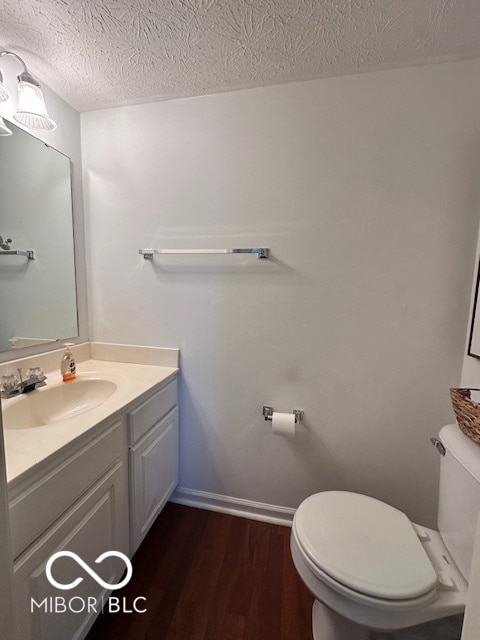 bathroom featuring vanity, toilet, a textured ceiling, and hardwood / wood-style floors