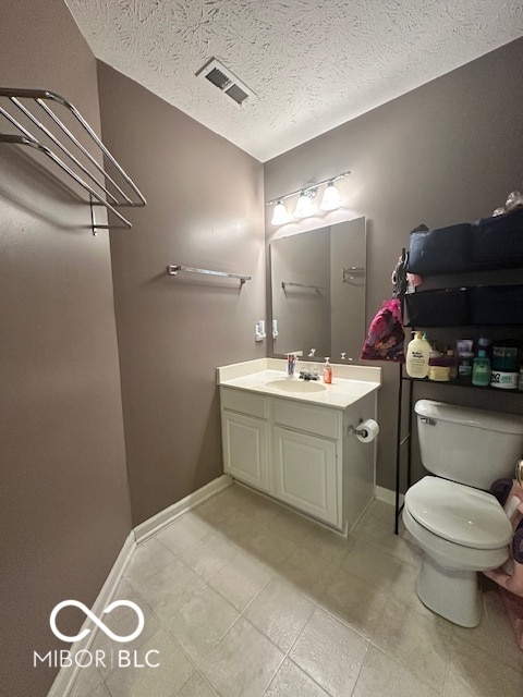 bathroom with vanity, toilet, and a textured ceiling