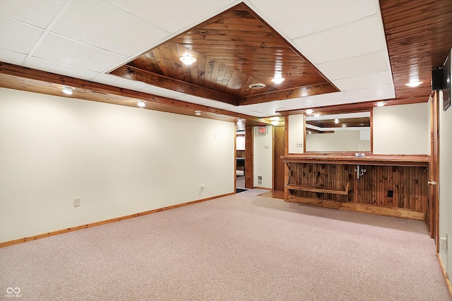 unfurnished living room featuring bar area, light carpet, and a raised ceiling