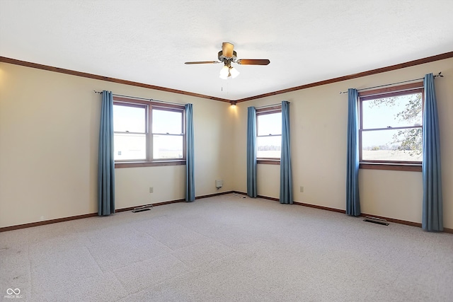 empty room with ornamental molding, ceiling fan, light colored carpet, and a healthy amount of sunlight