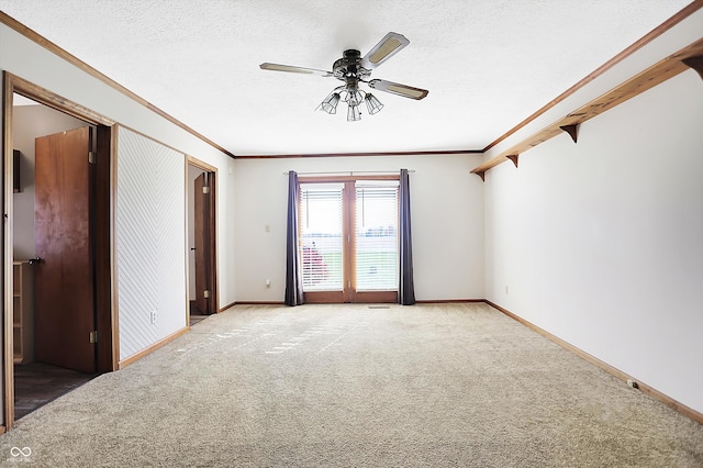 empty room with a textured ceiling, carpet flooring, ceiling fan, and crown molding