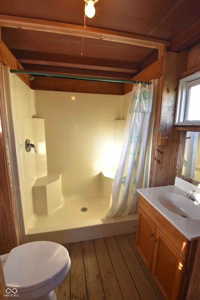 bathroom featuring toilet, curtained shower, wood walls, hardwood / wood-style flooring, and vanity