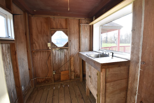 interior space with dark wood-type flooring, wood walls, sink, and wooden ceiling