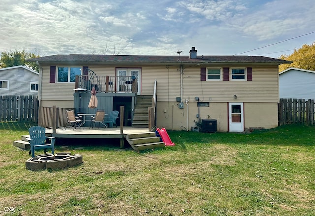 rear view of house featuring an outdoor fire pit, a deck, and a lawn