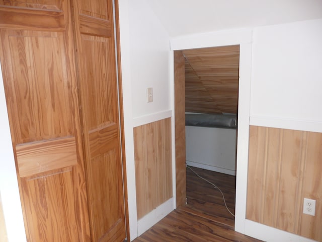 hall with dark wood-type flooring and wood walls