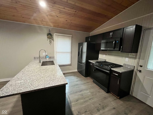 kitchen featuring lofted ceiling, kitchen peninsula, black appliances, light hardwood / wood-style floors, and sink