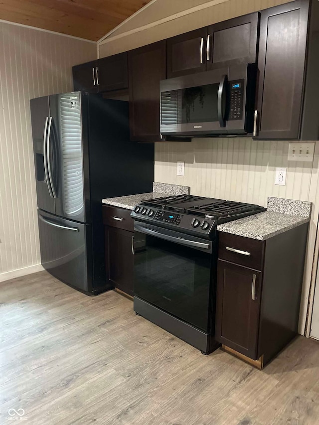 kitchen featuring light hardwood / wood-style floors, appliances with stainless steel finishes, dark brown cabinetry, and light stone counters