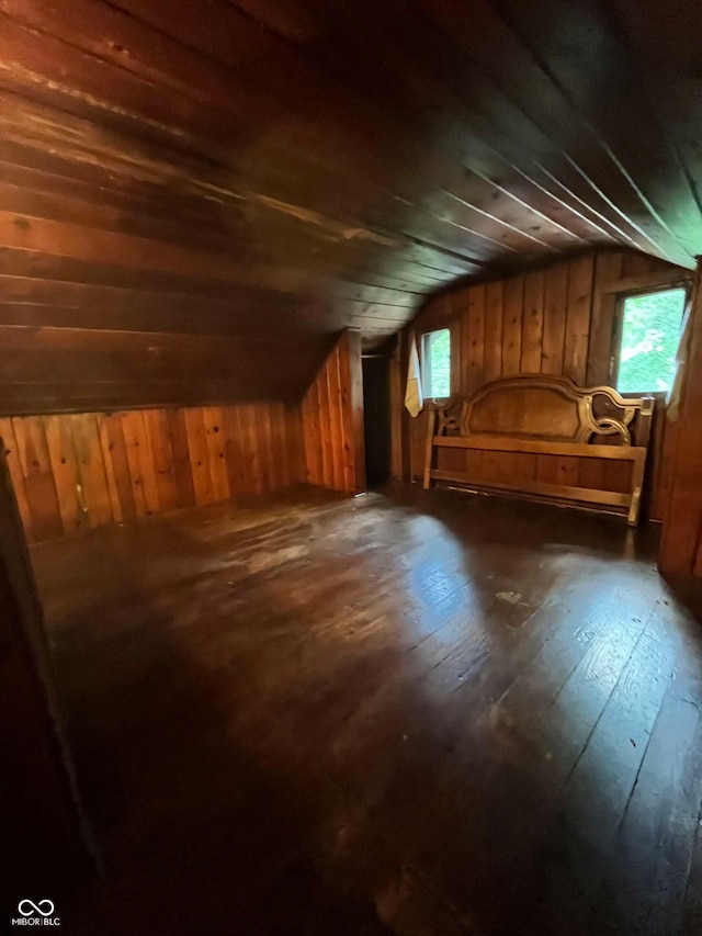 additional living space featuring dark hardwood / wood-style flooring, wood walls, and vaulted ceiling