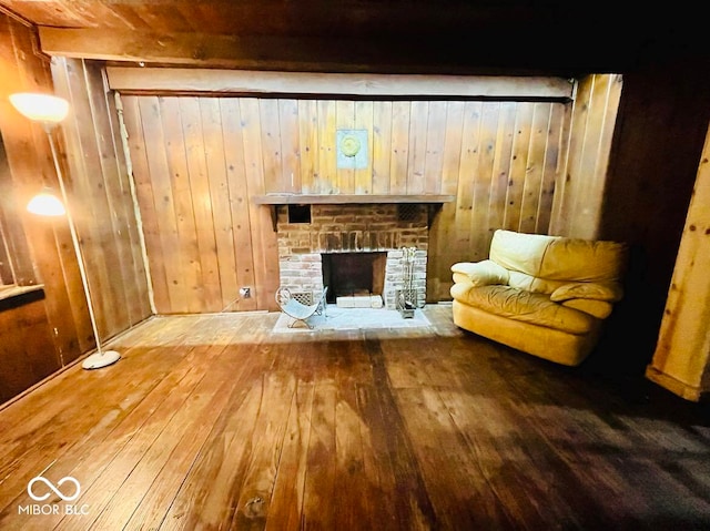 unfurnished room featuring hardwood / wood-style flooring, a brick fireplace, and wooden walls