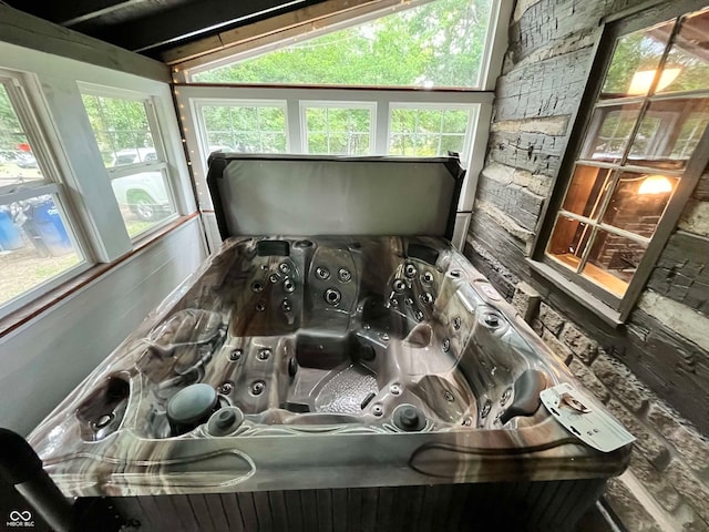 sunroom / solarium with a jacuzzi, lofted ceiling, and plenty of natural light