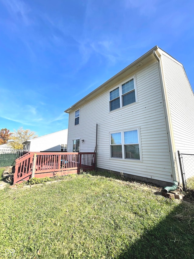 rear view of house featuring a wooden deck and a lawn