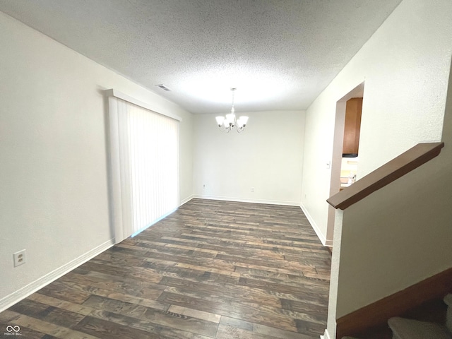 empty room featuring a textured ceiling, dark hardwood / wood-style flooring, and a chandelier