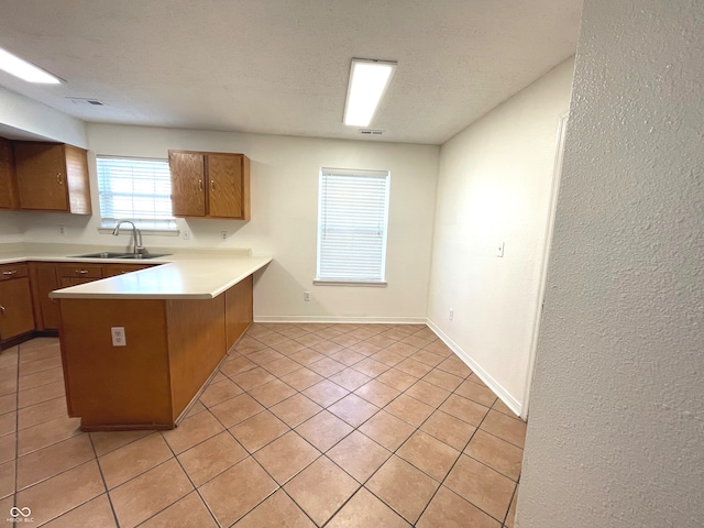 kitchen featuring sink, kitchen peninsula, a textured ceiling, and light tile patterned floors