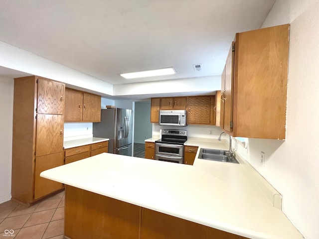 kitchen with sink, kitchen peninsula, stainless steel appliances, and light tile patterned floors