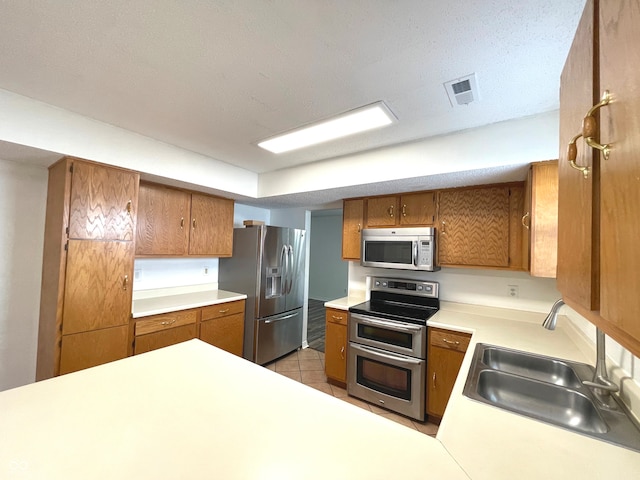 kitchen with sink, stainless steel appliances, a textured ceiling, and light tile patterned floors