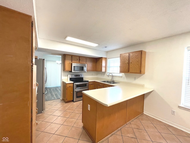 kitchen featuring sink, appliances with stainless steel finishes, kitchen peninsula, and light tile patterned flooring