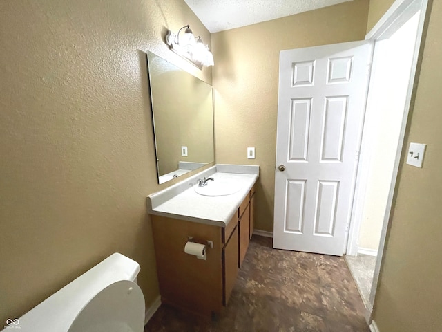 bathroom with vanity, toilet, and a textured ceiling