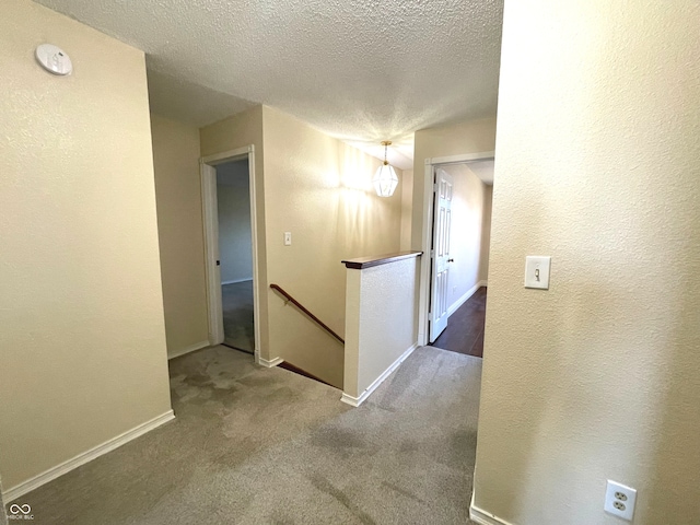 hallway with carpet and a textured ceiling