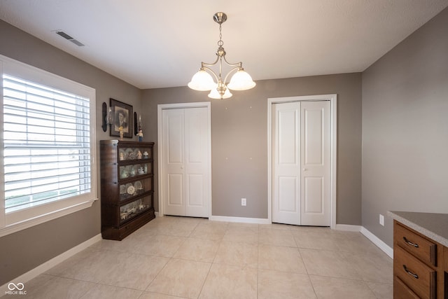 unfurnished dining area with a notable chandelier and light tile patterned floors