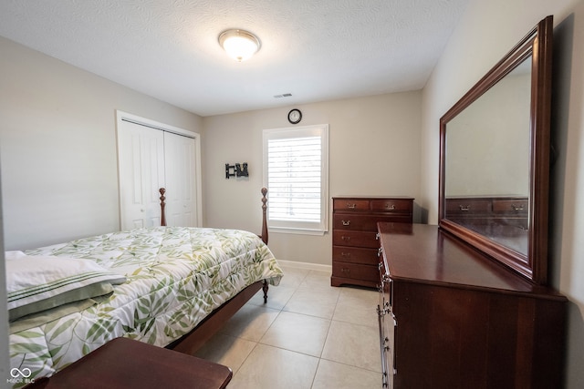 bedroom with light tile patterned floors, a textured ceiling, and a closet