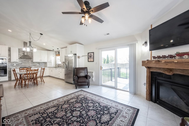 living room featuring sink, ceiling fan, vaulted ceiling, and light tile patterned flooring