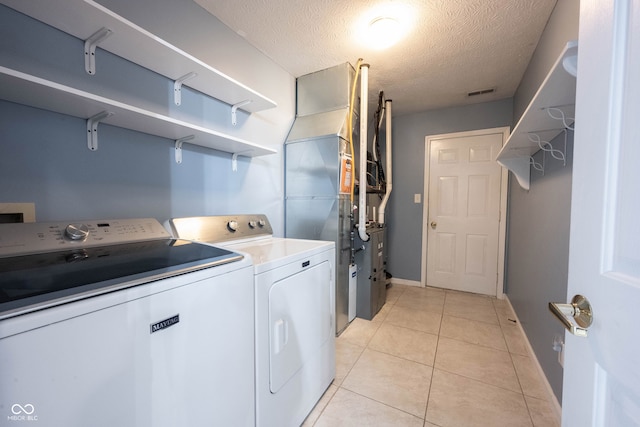 laundry room with light tile patterned floors, a textured ceiling, and washing machine and clothes dryer