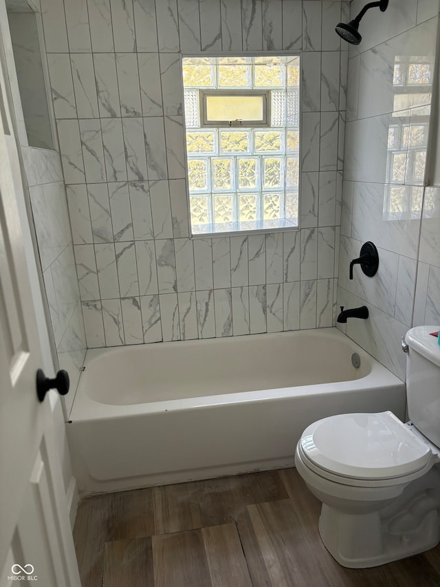 bathroom with hardwood / wood-style floors, tiled shower / bath combo, and toilet