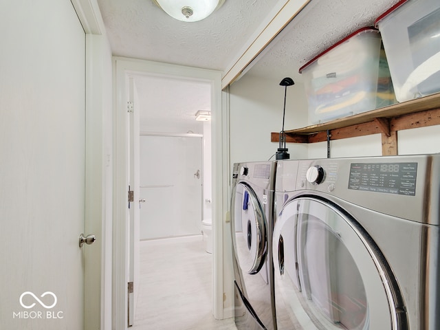 washroom featuring washing machine and dryer and a textured ceiling