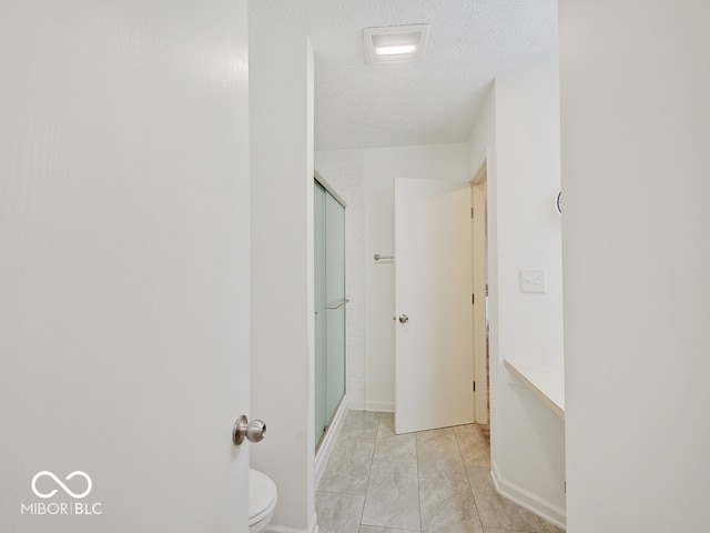 bathroom with walk in shower, tile patterned flooring, a textured ceiling, and toilet